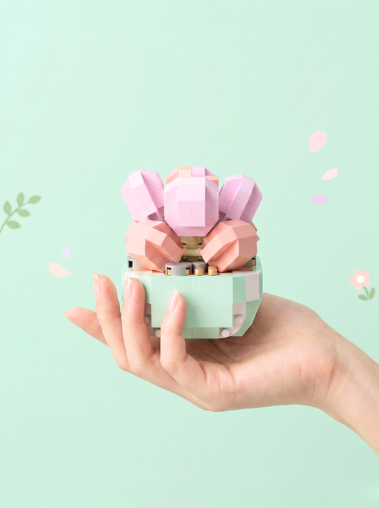 Hand holding a small pink and green container with a decorative flower on a light green background