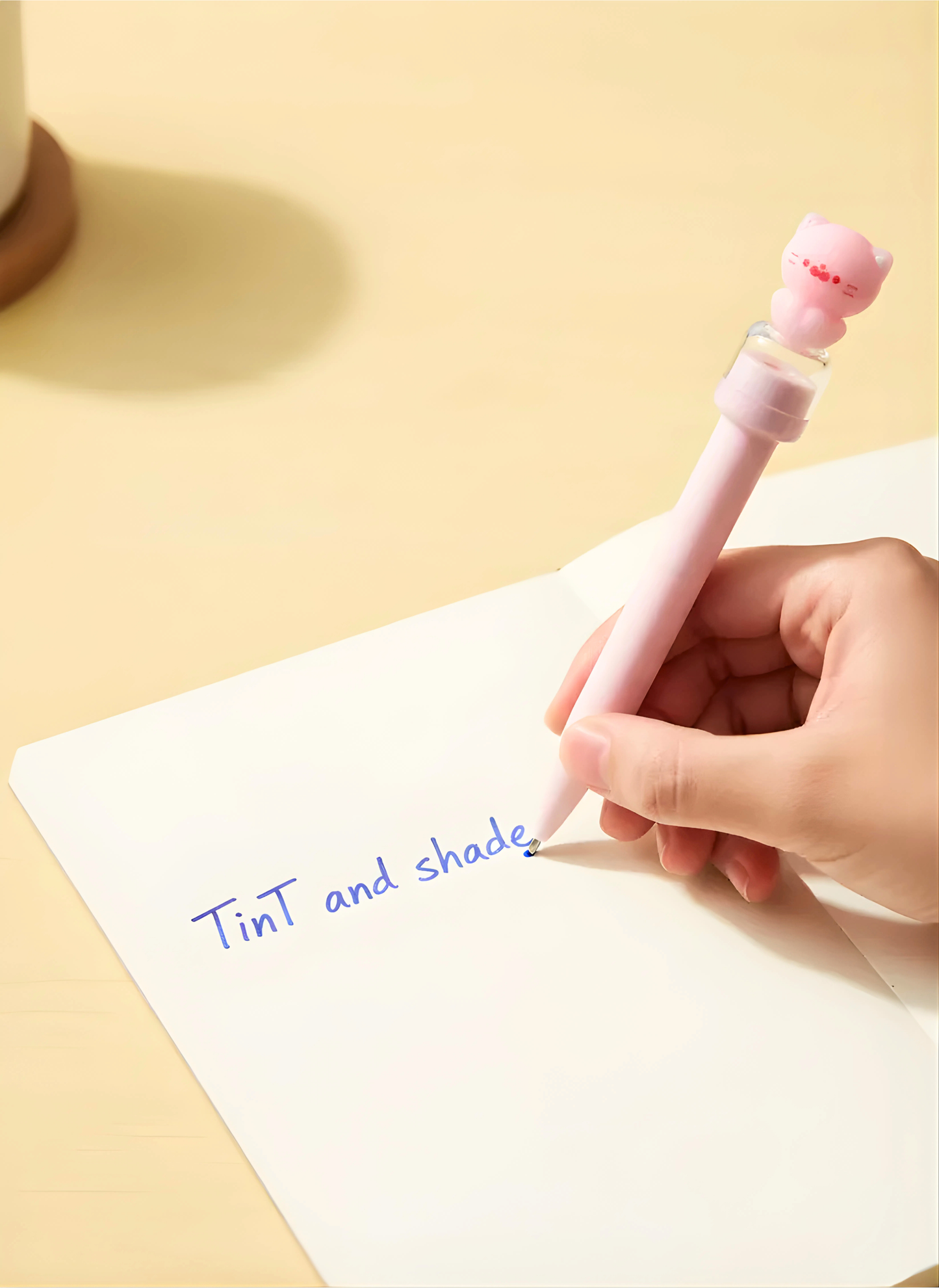 Hand holding a pink pen writing on a white sheet of paper with 'Tint and shade' text on a yellow background.