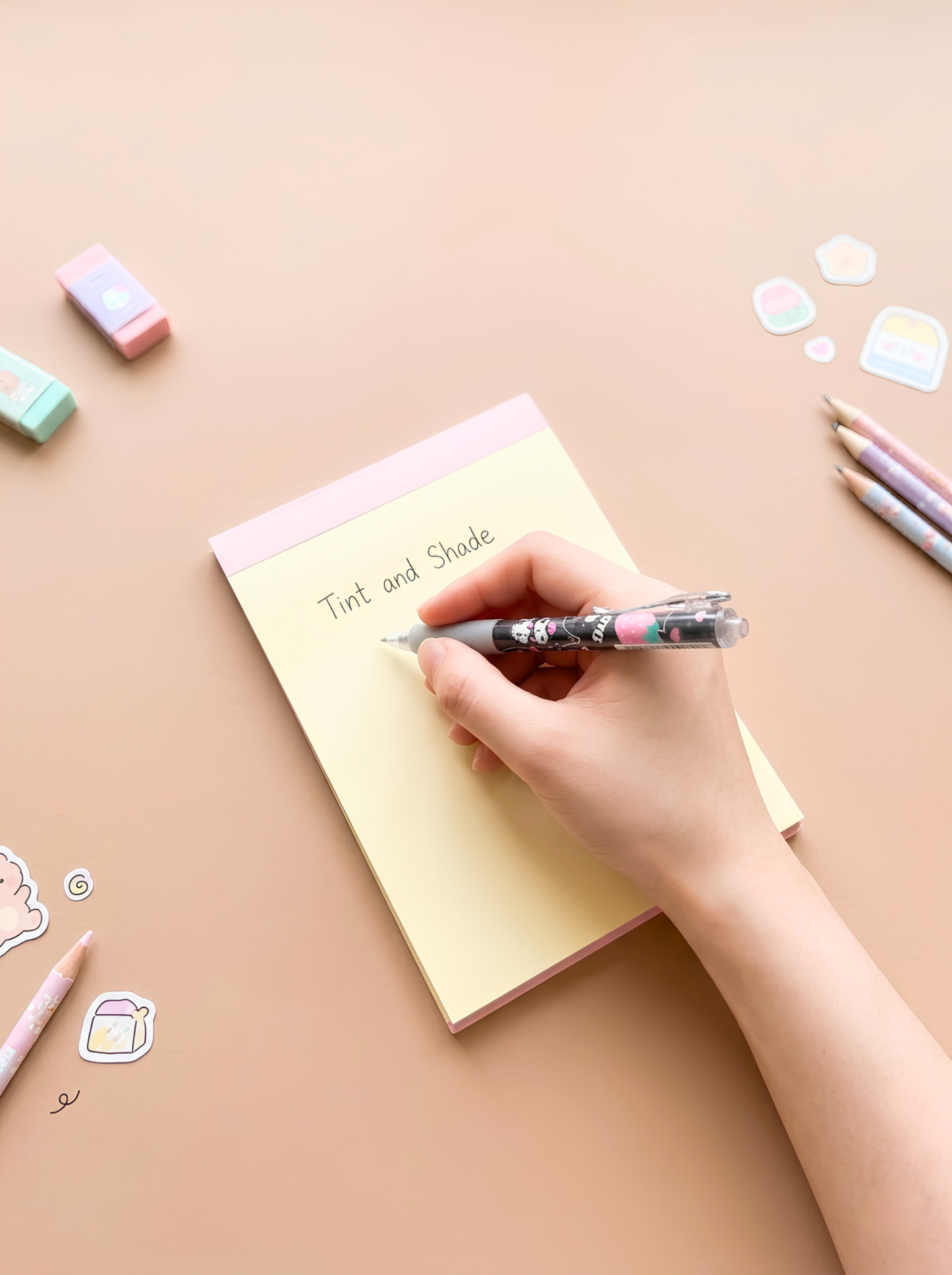 Hand writing on a notebook with colorful pens and erasers on a pastel background