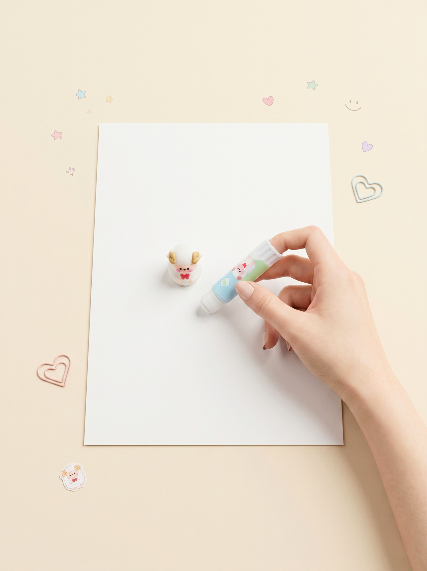 Hand holding a small white toy with colorful accents near a piece of paper on a light beige background.