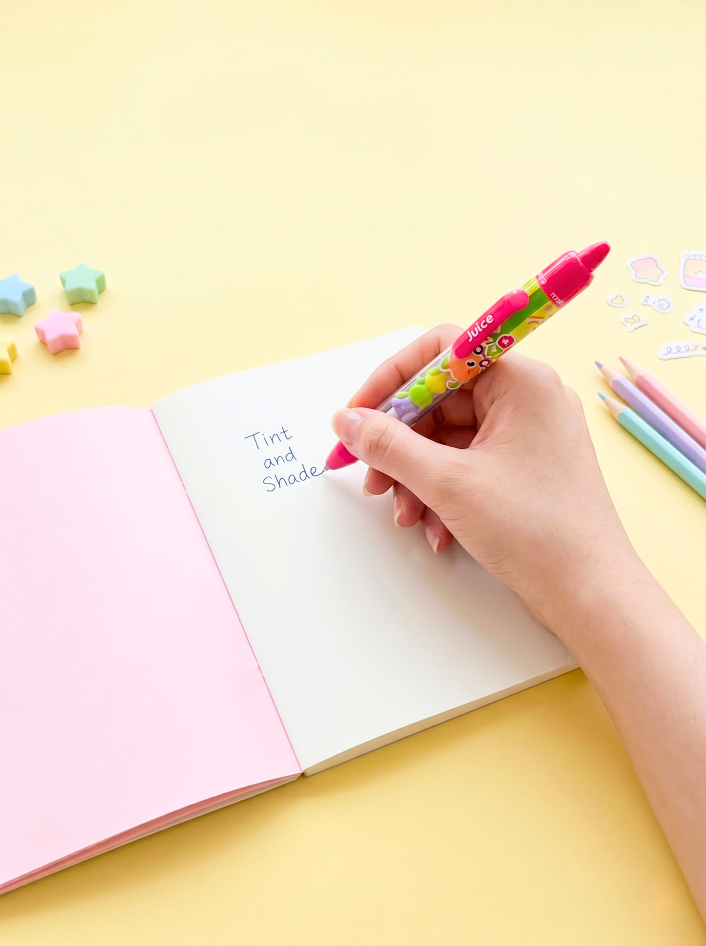 Hand holding a colorful marker over an open notebook with 'Tint and Shade' written inside, on a yellow background.