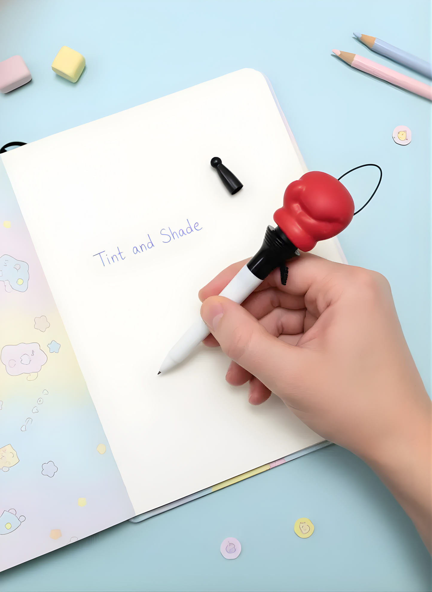 Hand holding a pen with a red and black握笔器 on a light blue background
