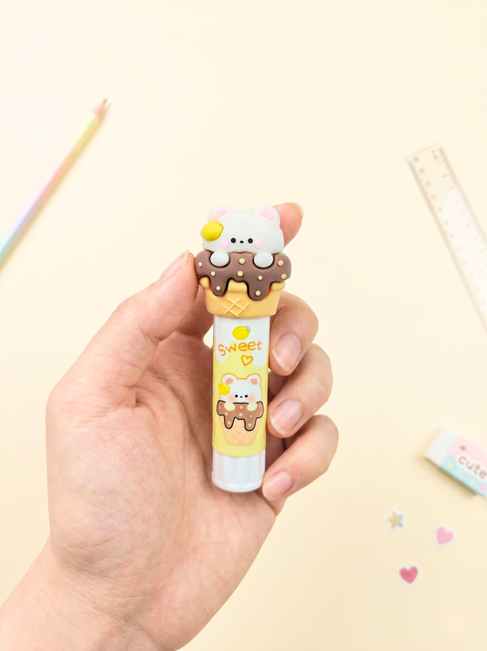 Hand holding a cute cartoon-style ice cream cone-shaped pen with a small character on a light background.