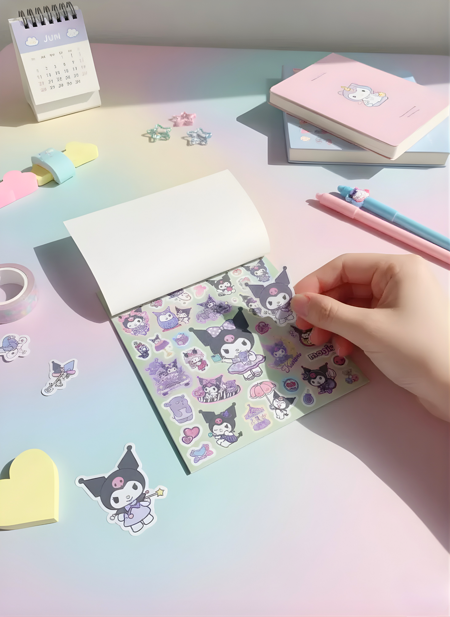 Hand holding a sheet of decorative stickers on a colorful desk with stationery items.