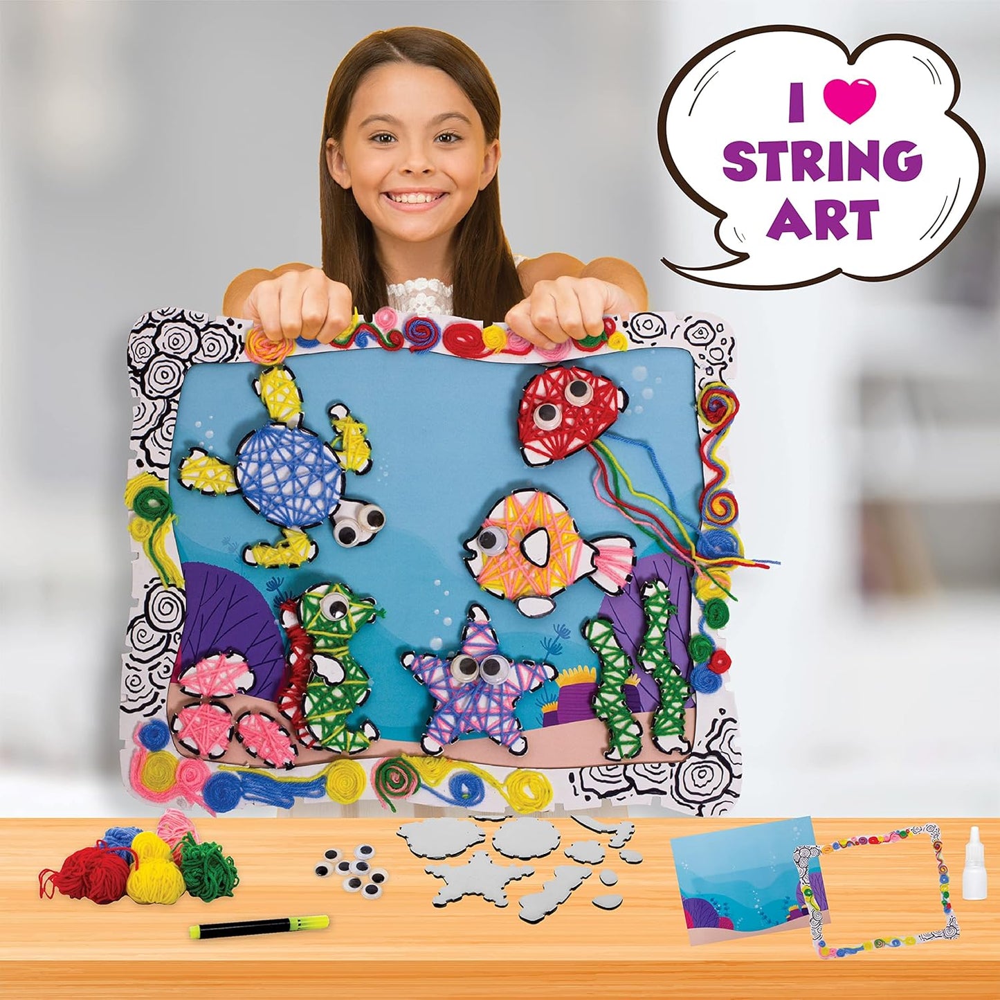 Child holding a colorful undersea scene craft project with various sea creatures and decorations.