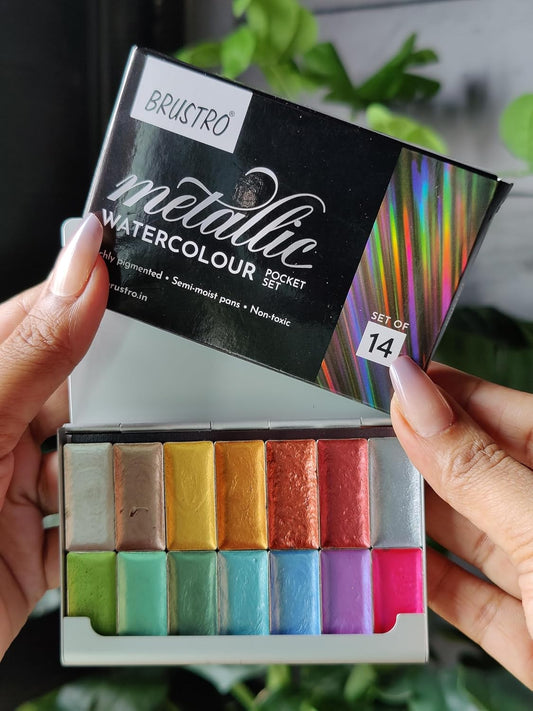 Brustro metallic watercolour pocket set with colorful pastels held by hands against a blurred background.