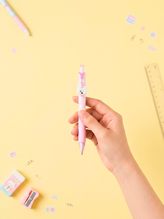 Hand holding a pink pen with a bear design on a yellow background