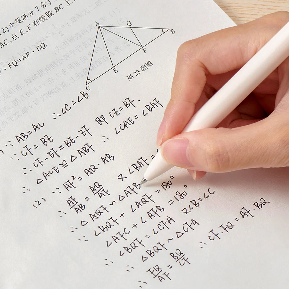 Hand holding a stylus over a piece of paper with mathematical equations and diagrams.