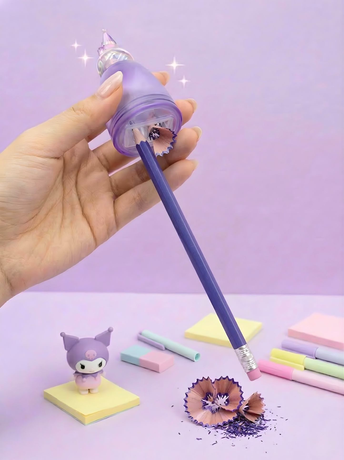 Hand holding a purple pencil with a decorative pencil sharpener against a light purple background