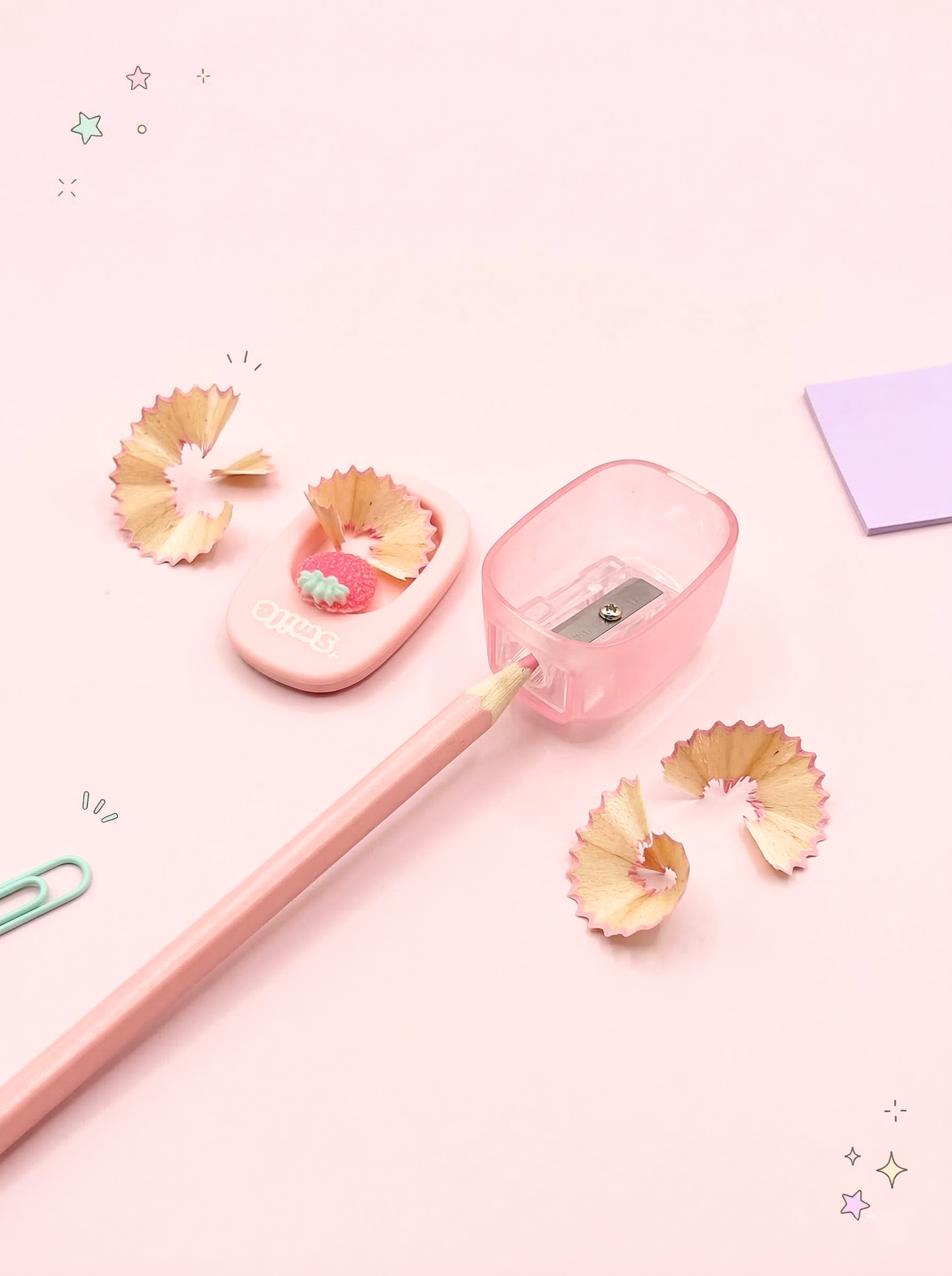Pink pencil with sharpener and pencil shavings on a light pink background