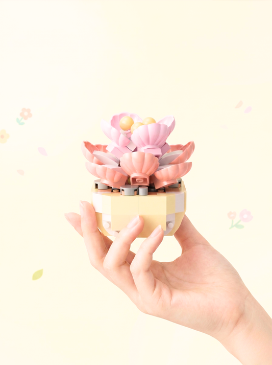 Hand holding a small pink and yellow decorative item against a light background