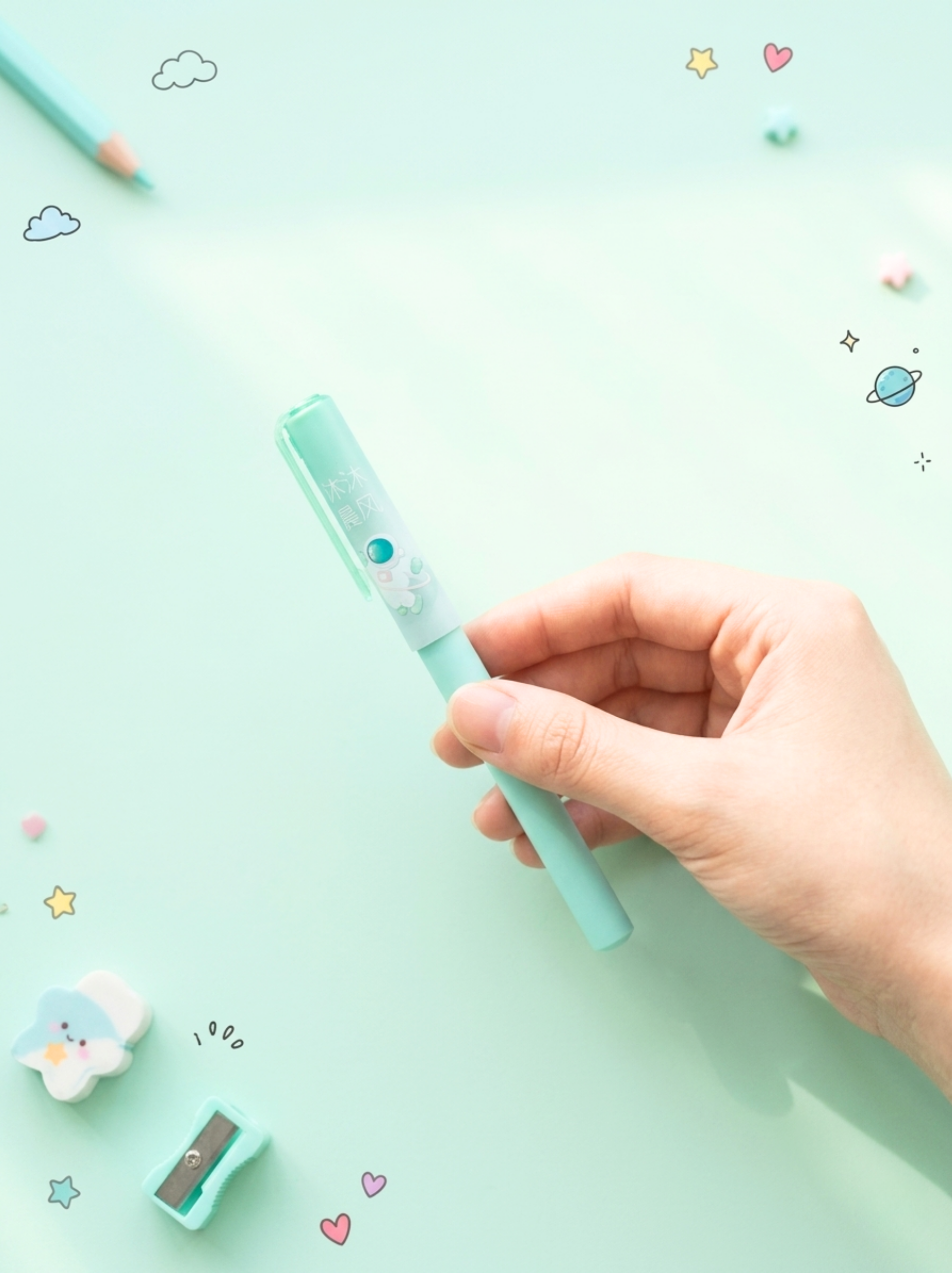 Hand holding a light blue pen on a light green background with cartoon illustrations.