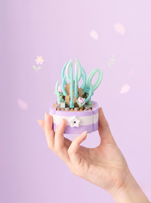 Hand holding a small decorative plant with a purple pot against a light purple background