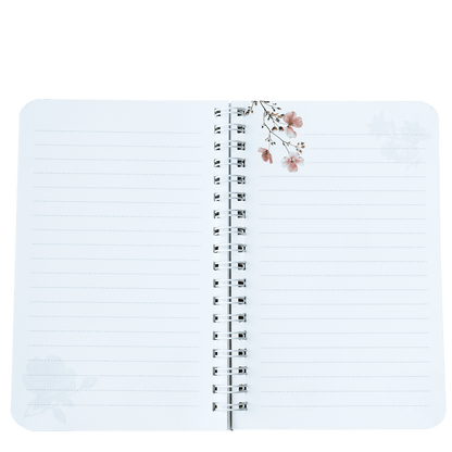 Open notebook with lined pages and floral design on a white background