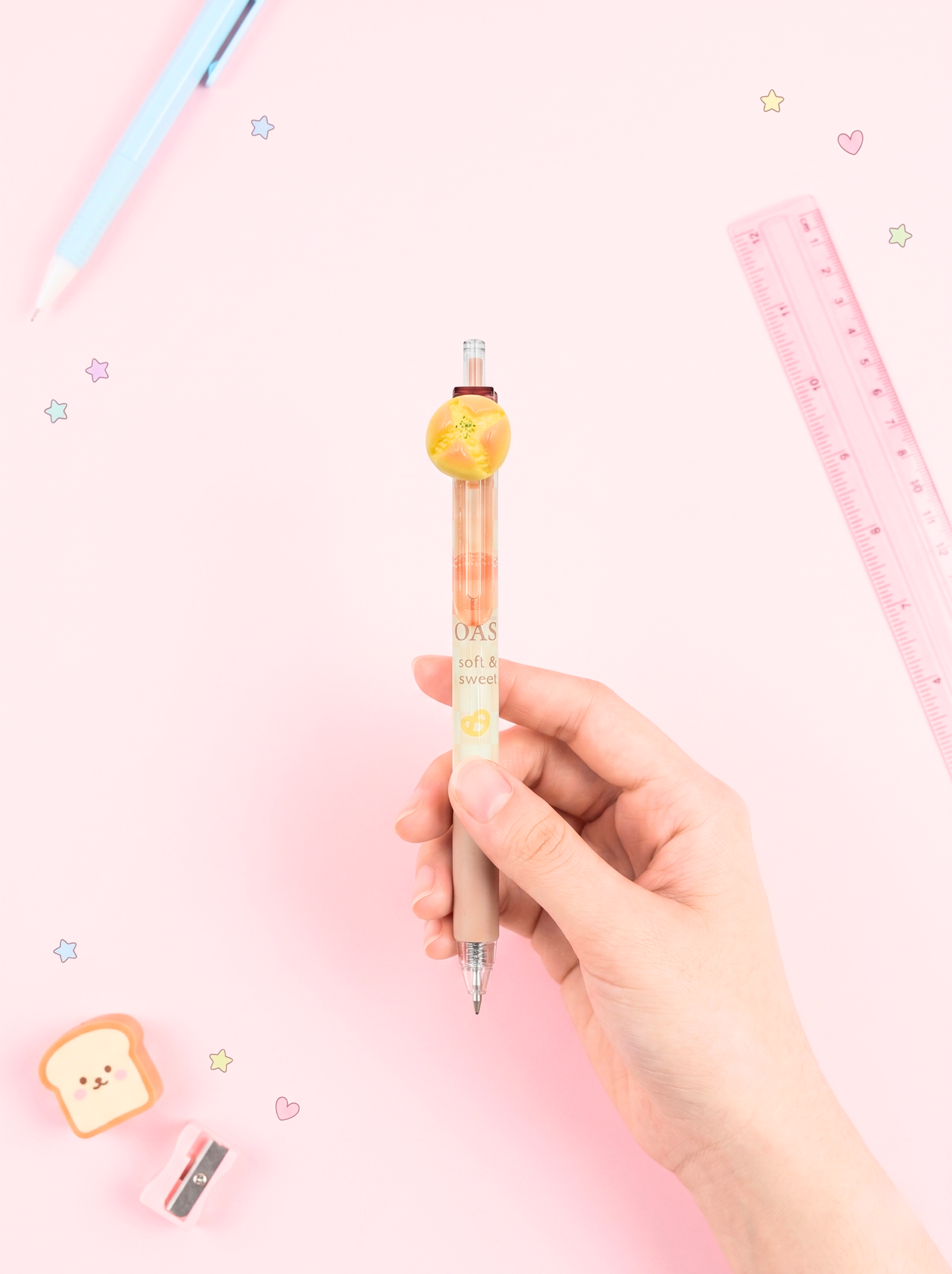 Hand holding a small mechanical pencil with a cute design on a pink background