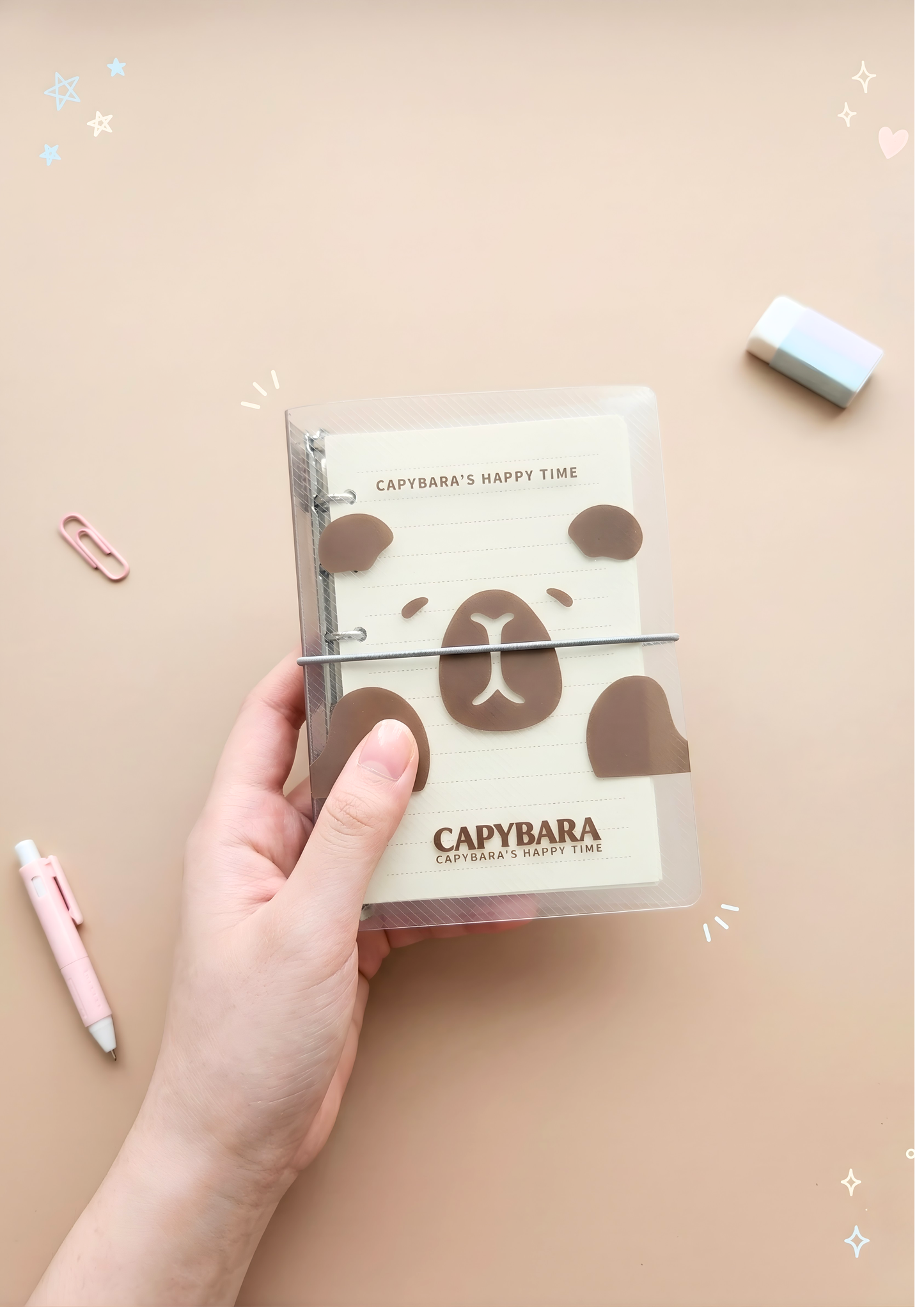 Capybara-themed notebook held by a hand on a beige background