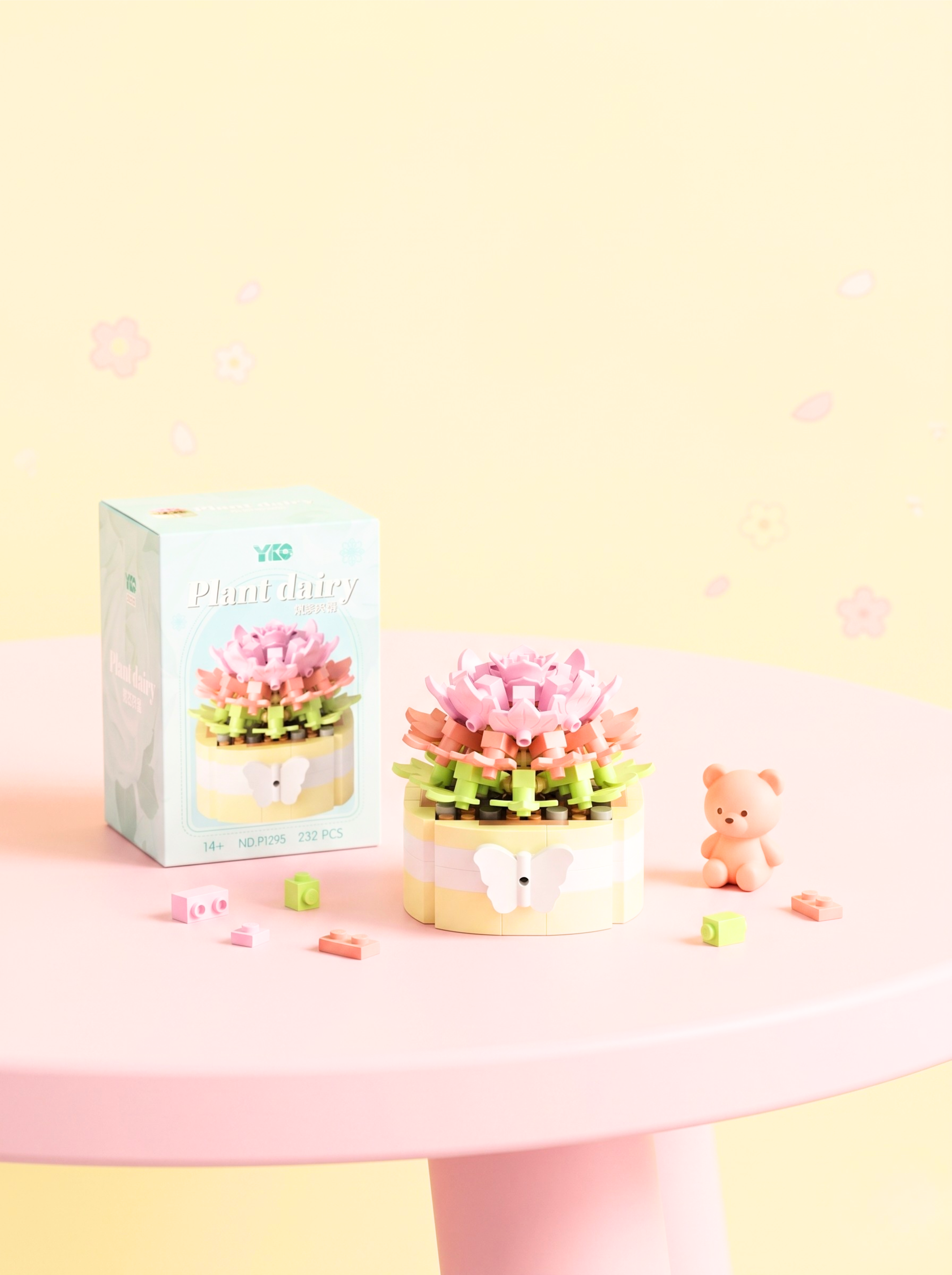 Decorative flower pot with a teddy bear and packaging on a pink surface with a light yellow background