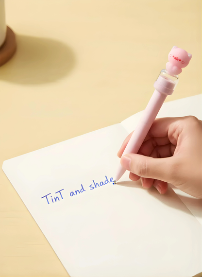 Person writing on a notepad with a pink pen featuring a cat-shaped clip.