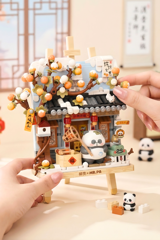 Hand holding a small model of a traditional Japanese building with panda characters on a wooden stand.