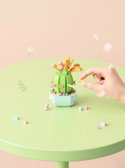 Hand interacting with a small green cactus-like plant on a light green table.