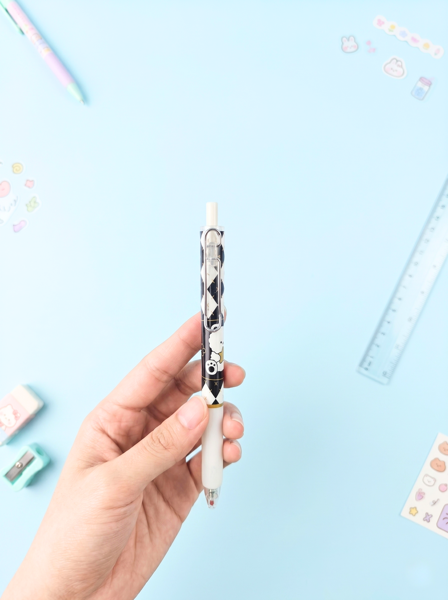 Hand holding a decorative pen with stationery items on a light blue background