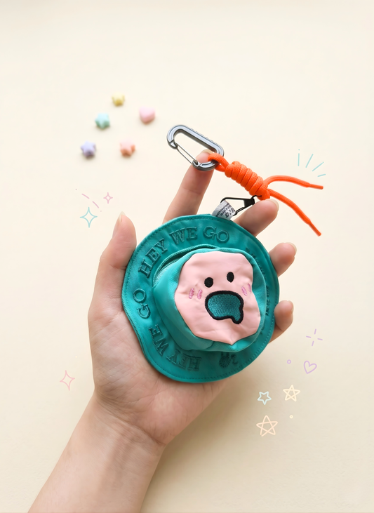 Teal keychain with pink dog tag held in a hand against a light background