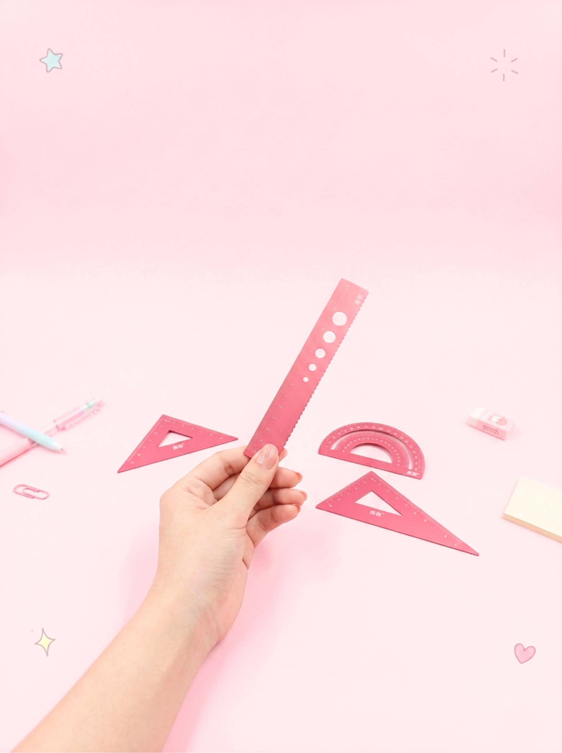 Hand holding a pink ruler against a pink background with geometric shapes.