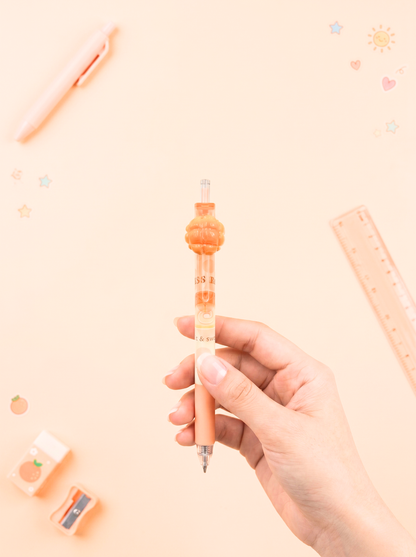 Hand holding a pen with a decorative cap on a light pink background