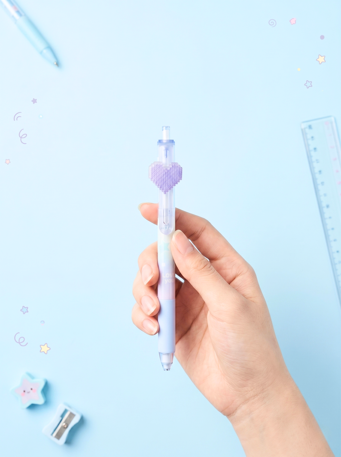 Hand holding a pen with a heart design on a light blue background