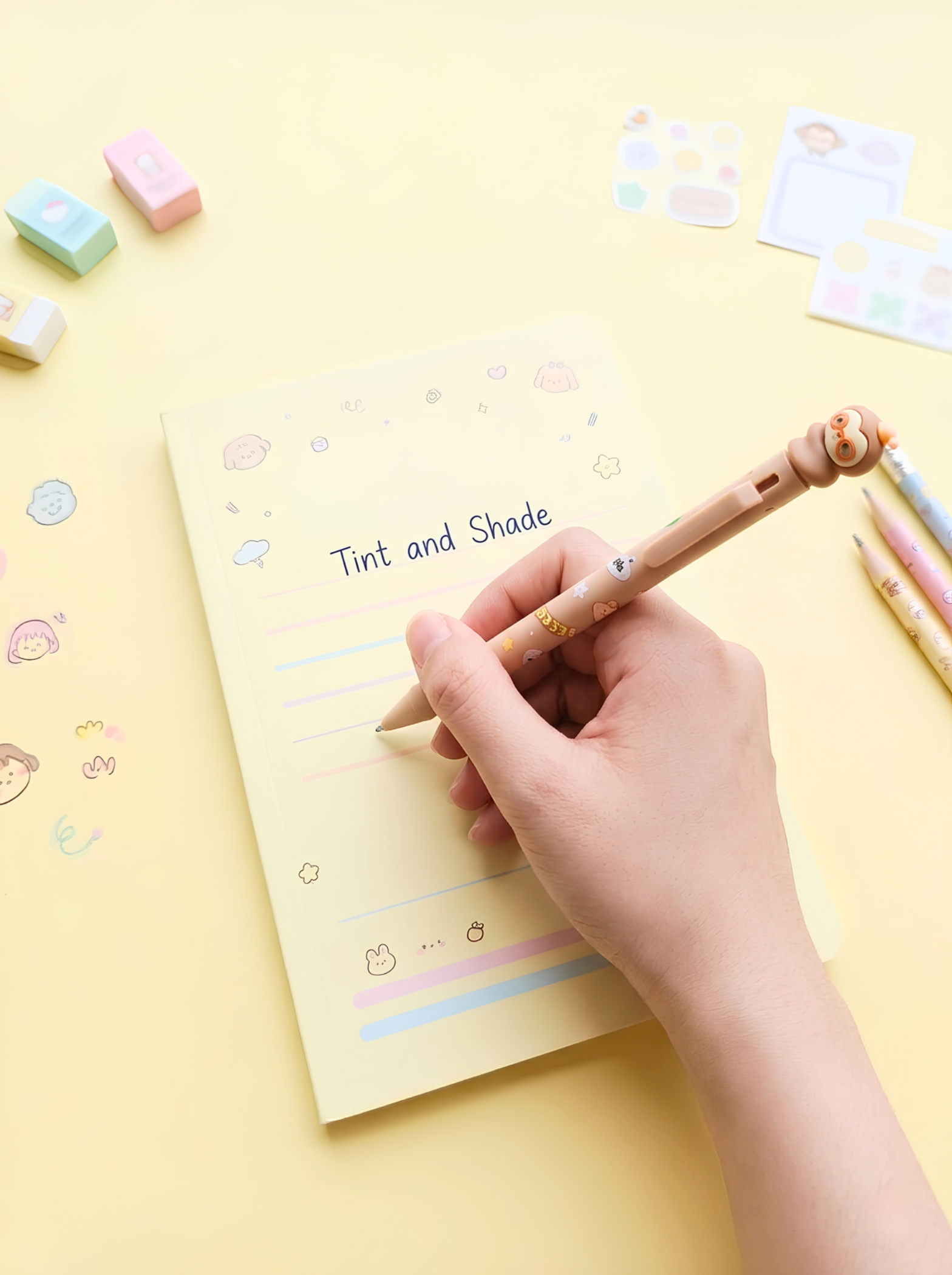 Hand holding a pen over a notepad with 'Tint and Shade' text on a yellow background with stationery items.