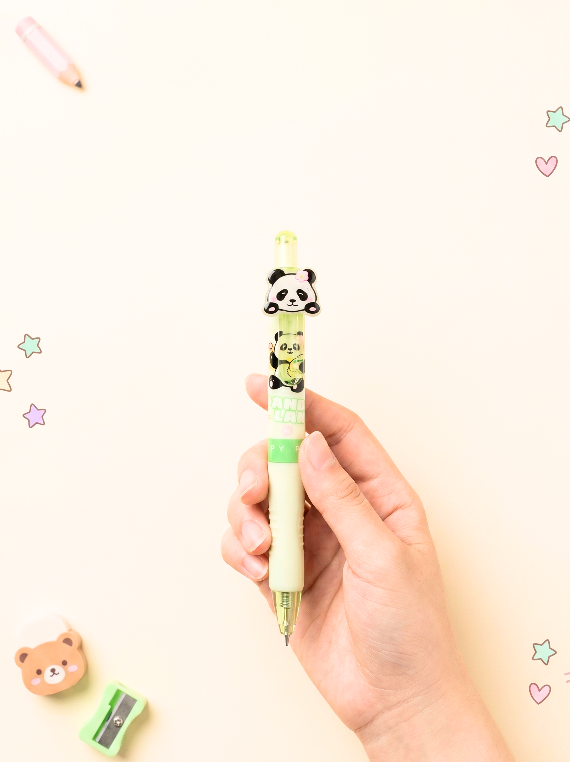 Hand holding a cartoon panda pen with decorative elements on a light background