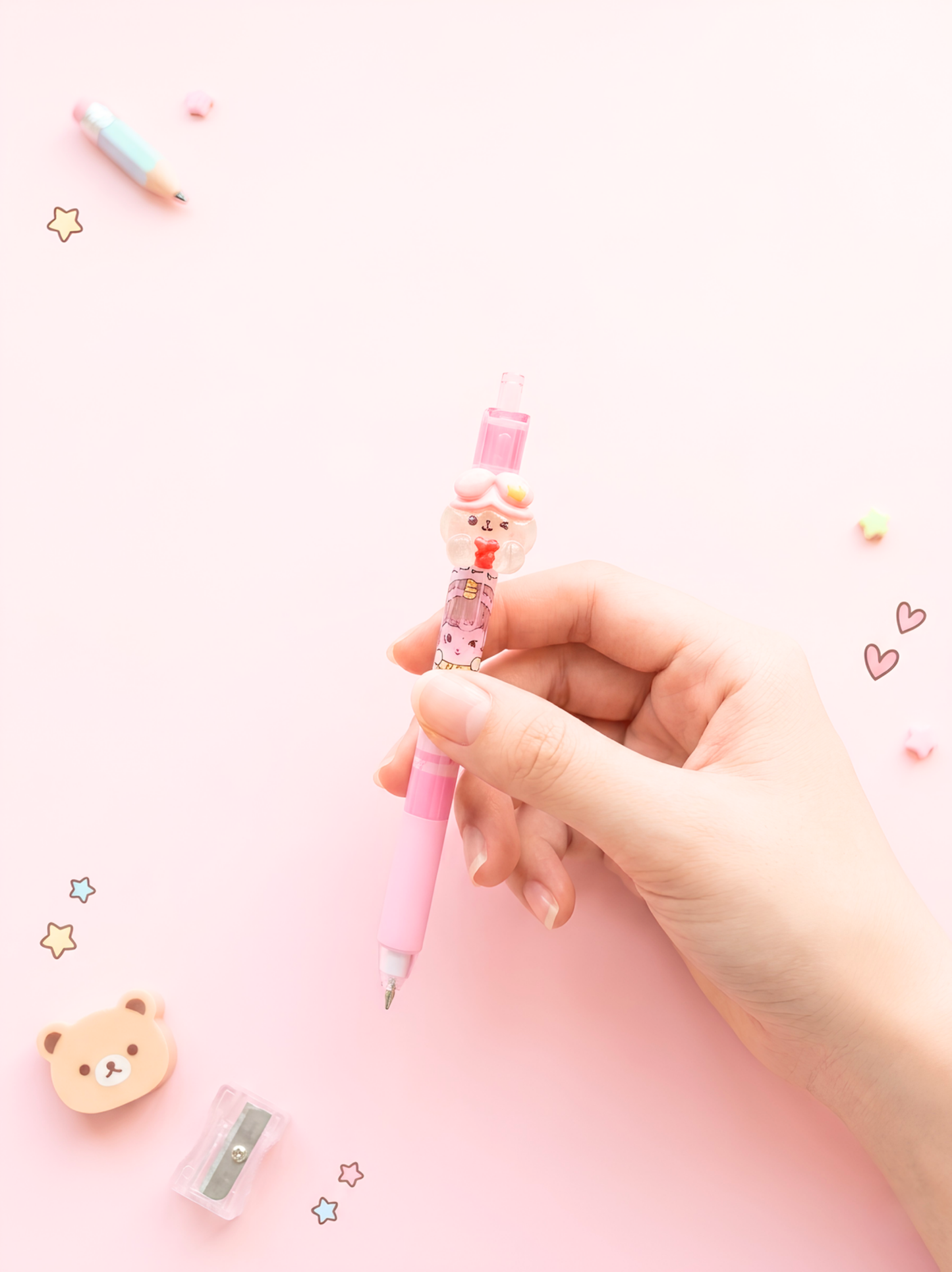 Hand holding a pink cartoon-themed pen with a small bear design on a light pink background.