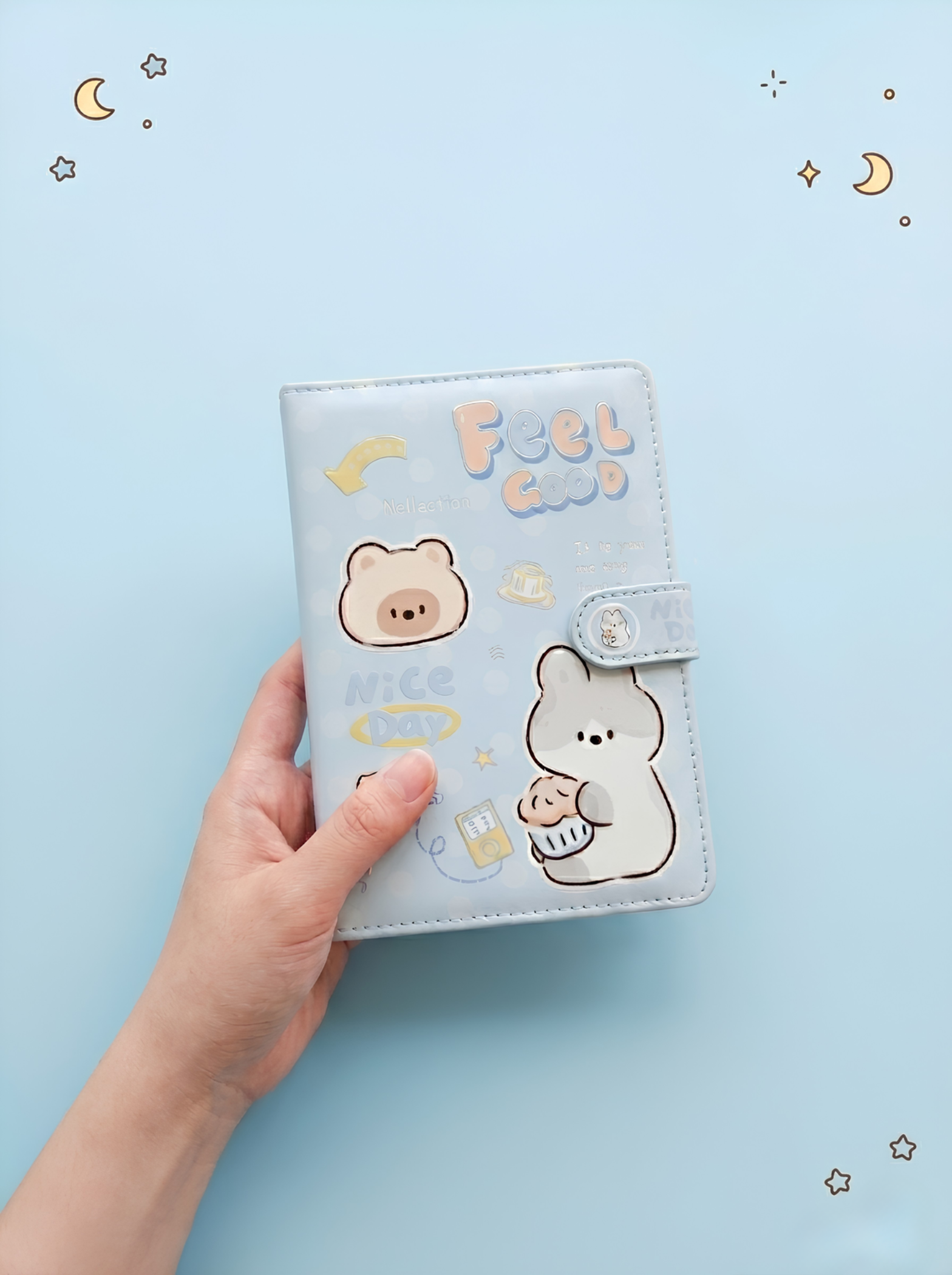 Light blue notebook with cartoon bear design held by a hand on a light blue background