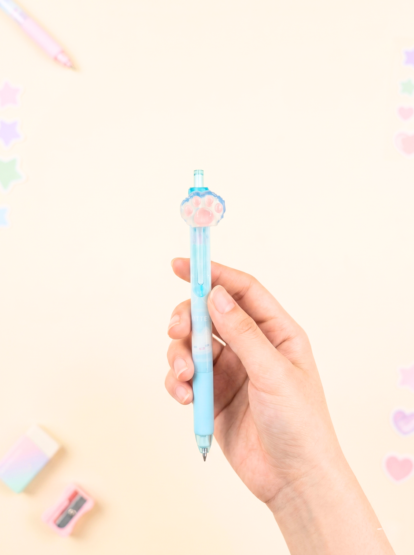 Hand holding a light blue pen with a decorative cap against a pastel background