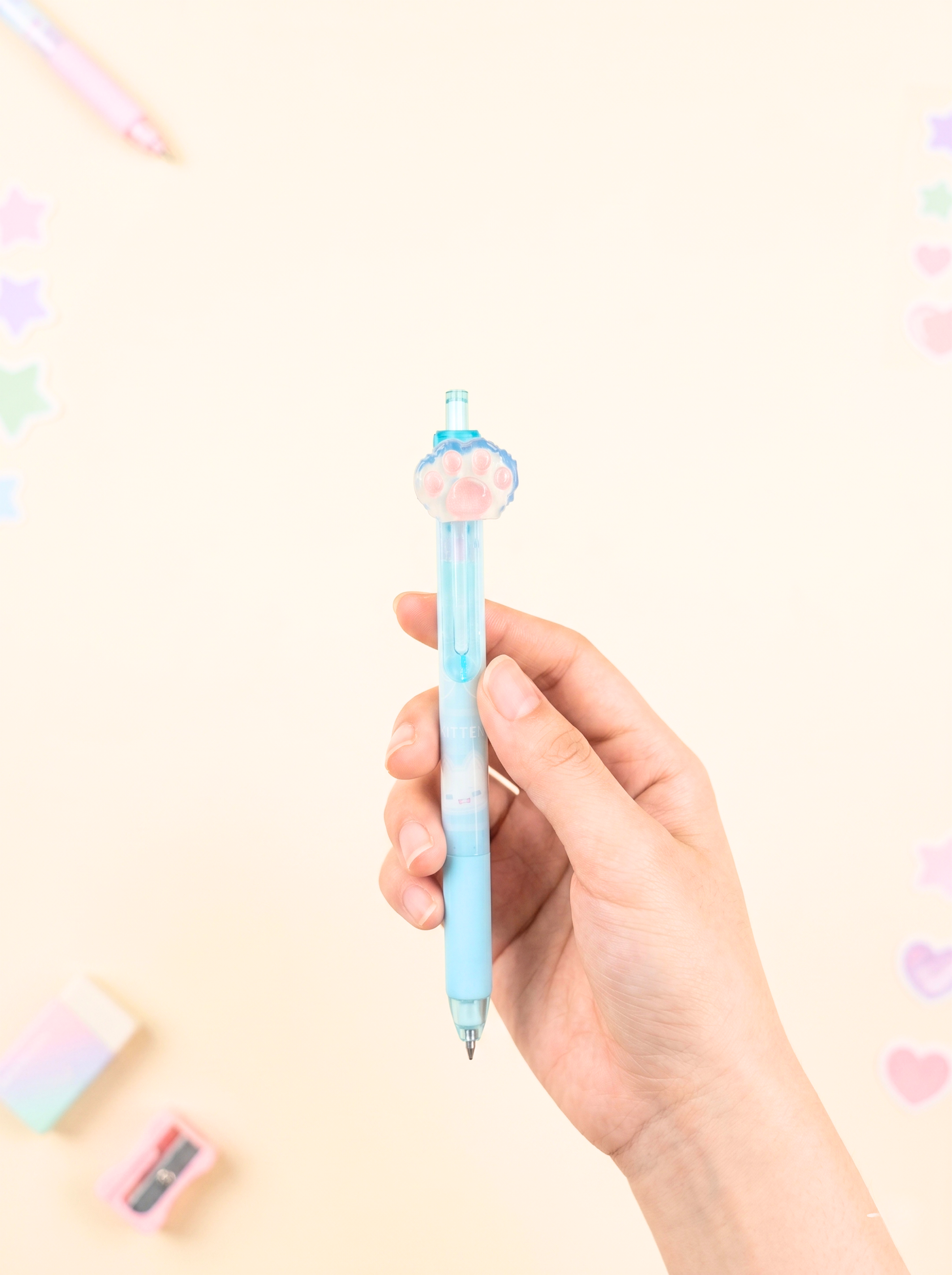 Hand holding a light blue pen with a decorative cap against a pastel background