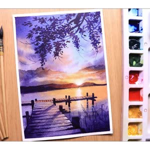 Watercolor painting of a dock by a lake with a sunset, next to a watercolor set.
