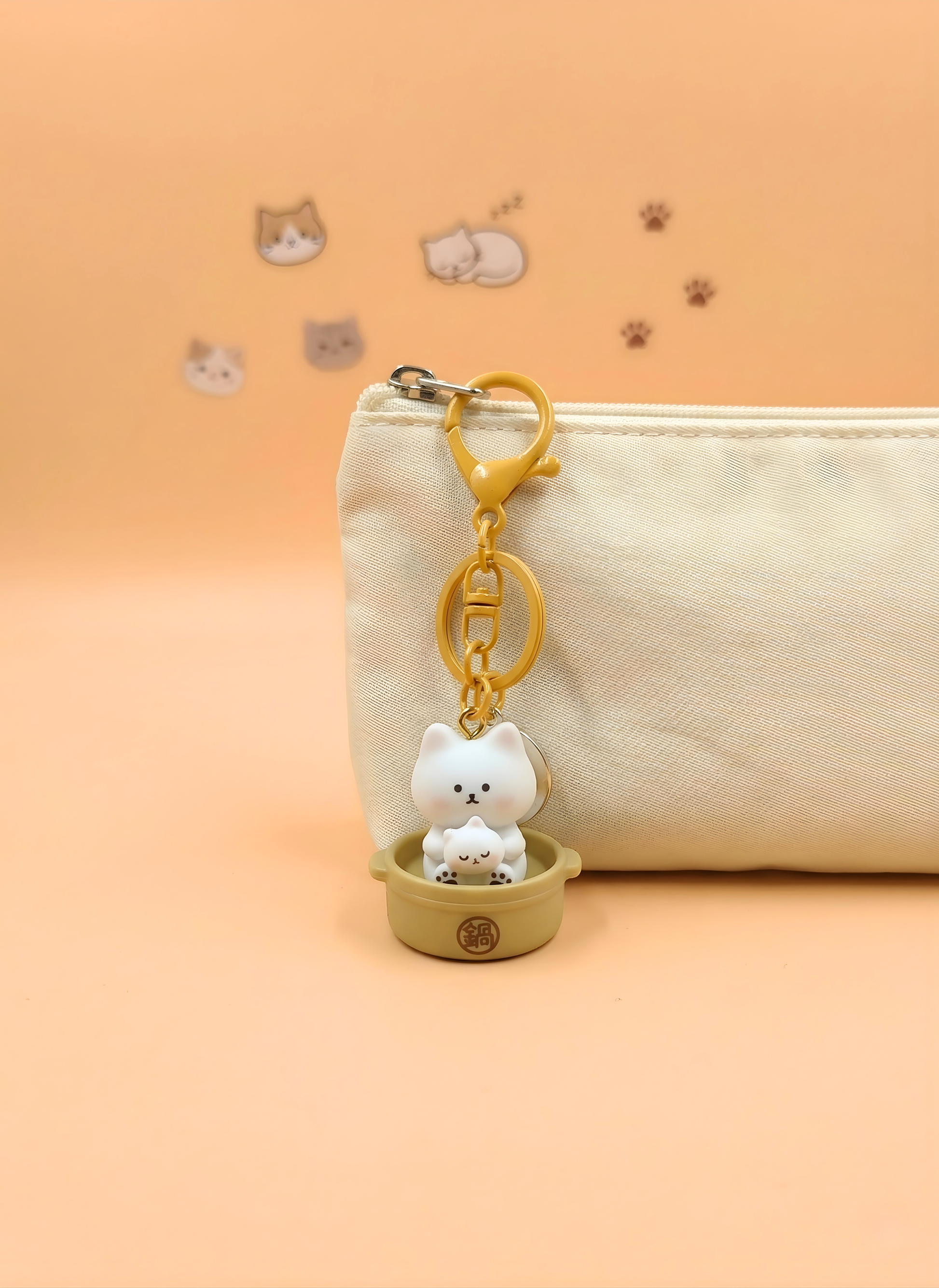 Cat-shaped keychain on a beige pouch with a soft orange background