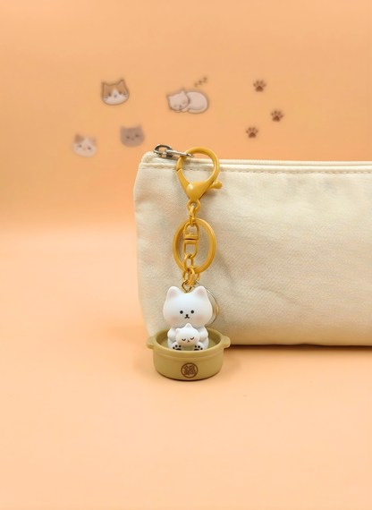Cat-shaped keychain on a beige pouch with a soft orange background