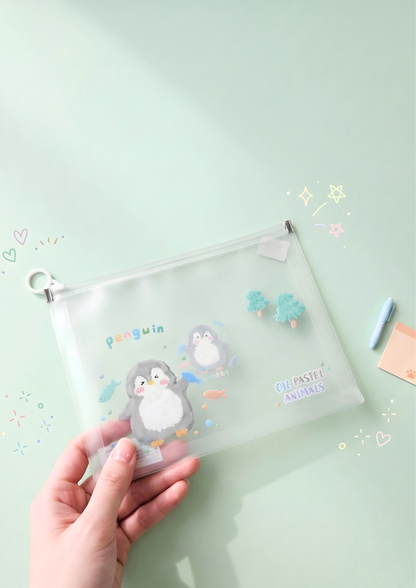 Clear pouch with penguin design held by a hand on a light green background
