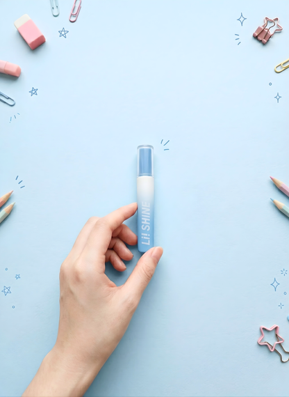 Hand holding a blue lip balm against a light blue background with decorative items.