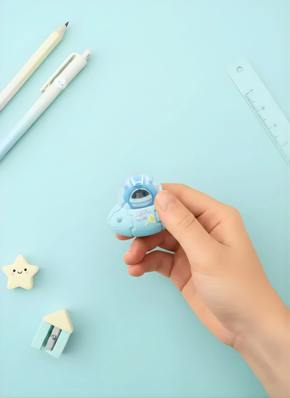 Hand holding a small blue cartoon-like object with stationery items on a light blue background