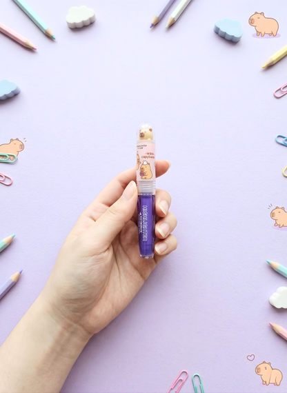 Hand holding a small bottle with a colorful background featuring stationery items.