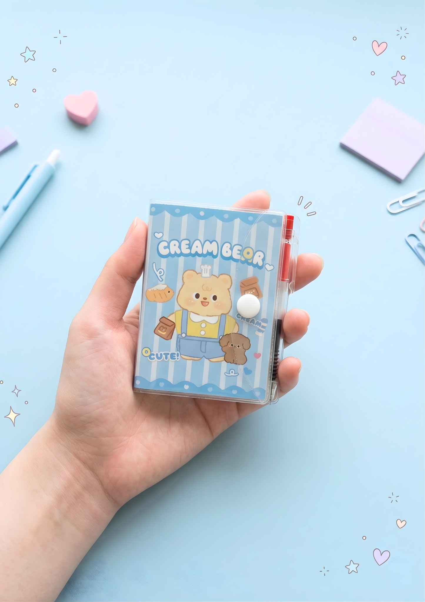 Hand holding a small blue notebook with cartoon bear design on a light blue background