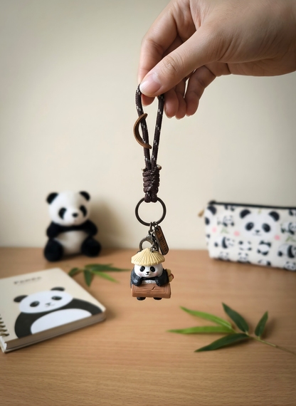 Hand holding a keychain with a panda design on a wooden surface.