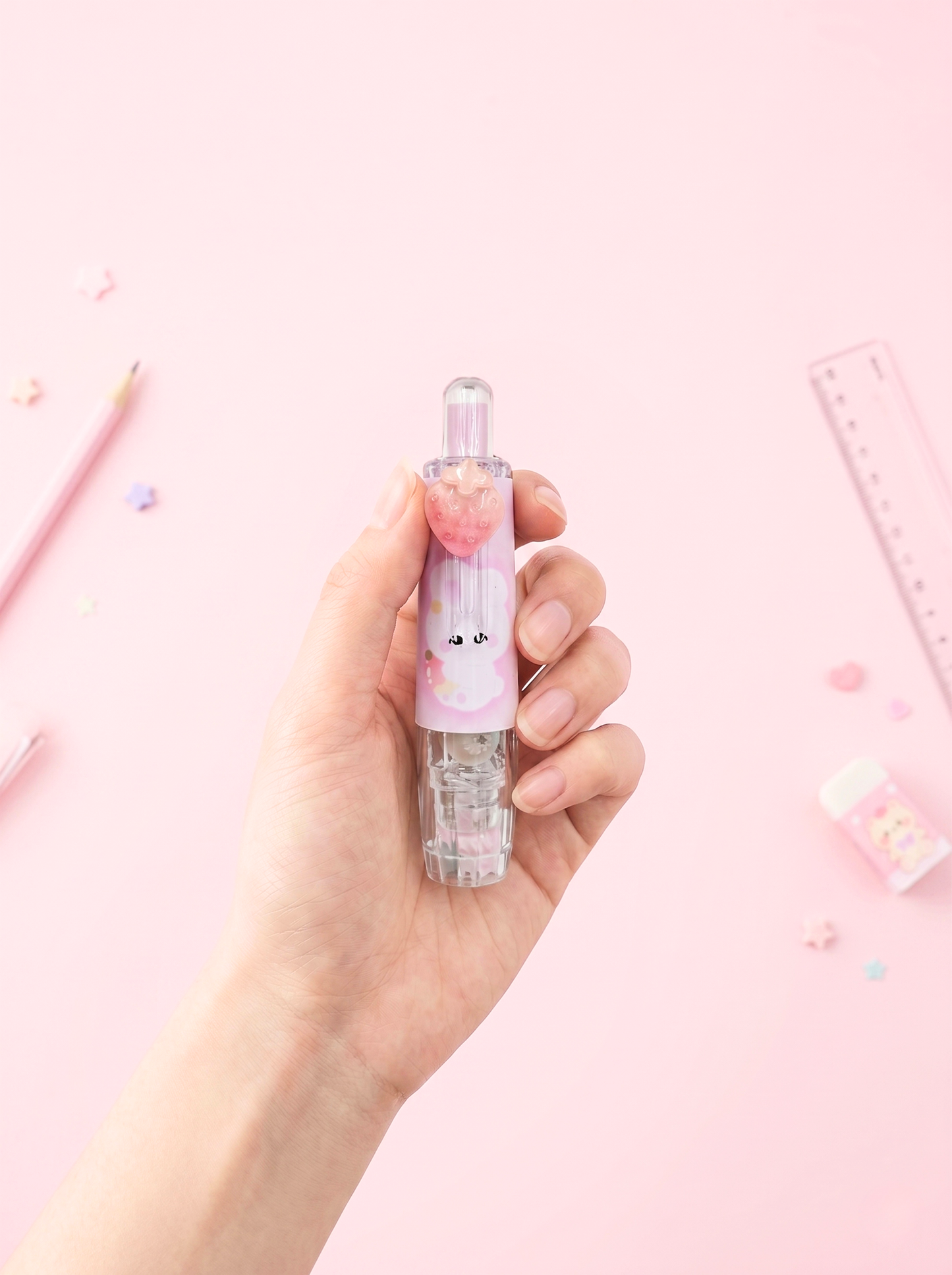 Hand holding a small bottle with a cute design on a pink background