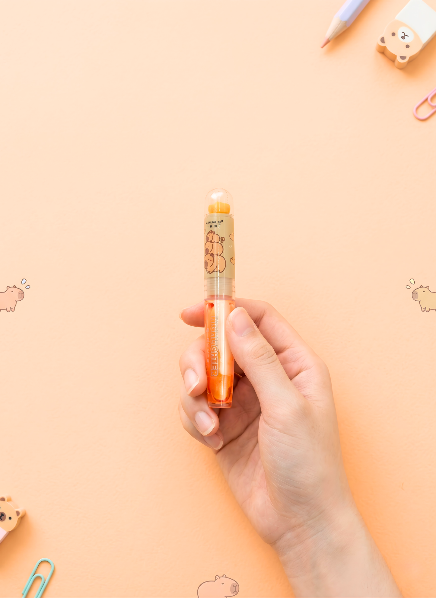 Hand holding a small orange object against a peach-colored background