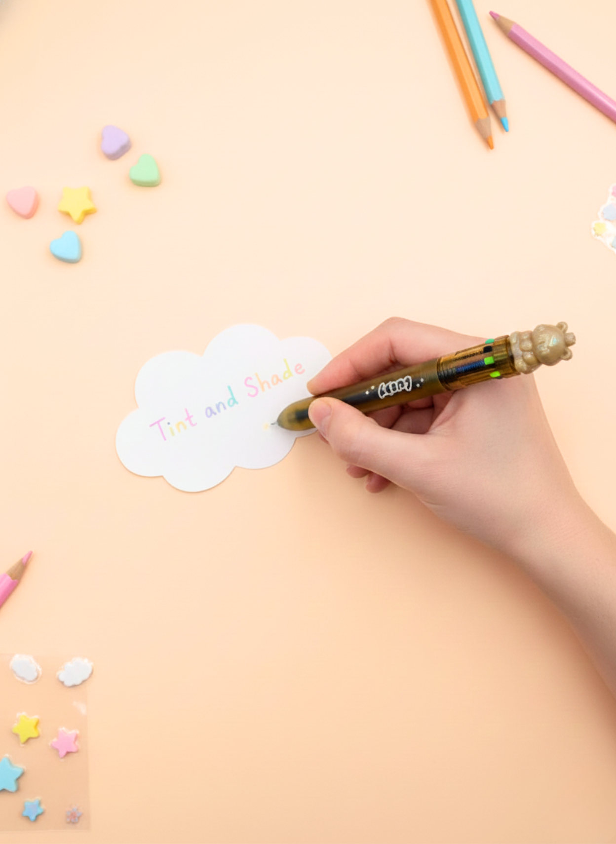 Hand writing on a cloud-shaped paper with colorful markers and stickers on a light brown background