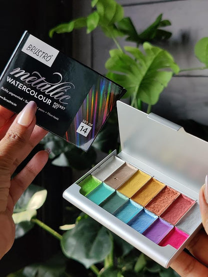 Brustro metallic watercolor set with open palette of colors held by a person against a plant background