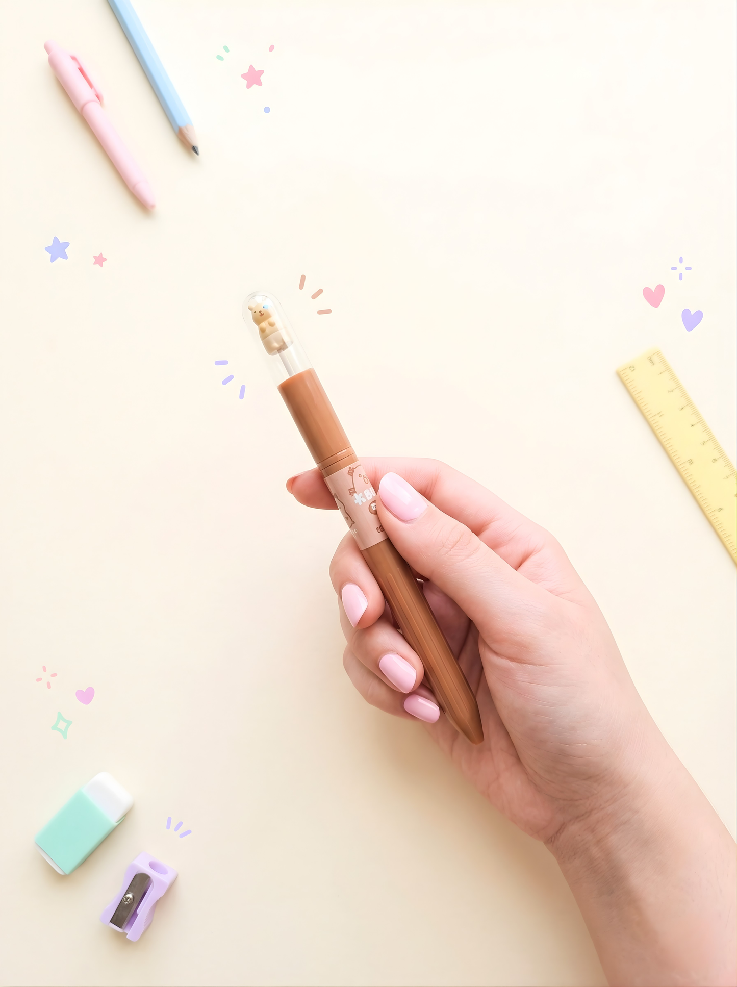 Hand holding a brown pen with colorful pencils and eraser on a light background