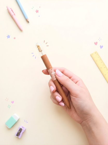 Hand holding a brown pen with colorful pencils and eraser on a light background